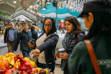 a group of people looking at a fruit stand